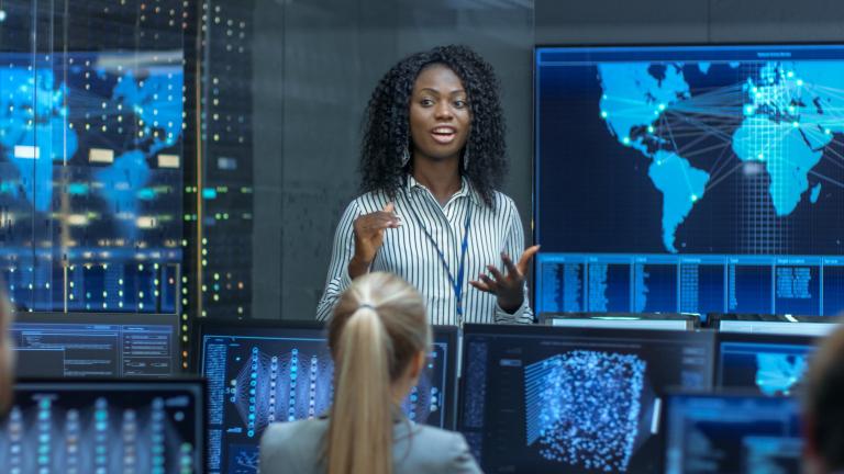 African American Woman talking to her team of tech professionals. 